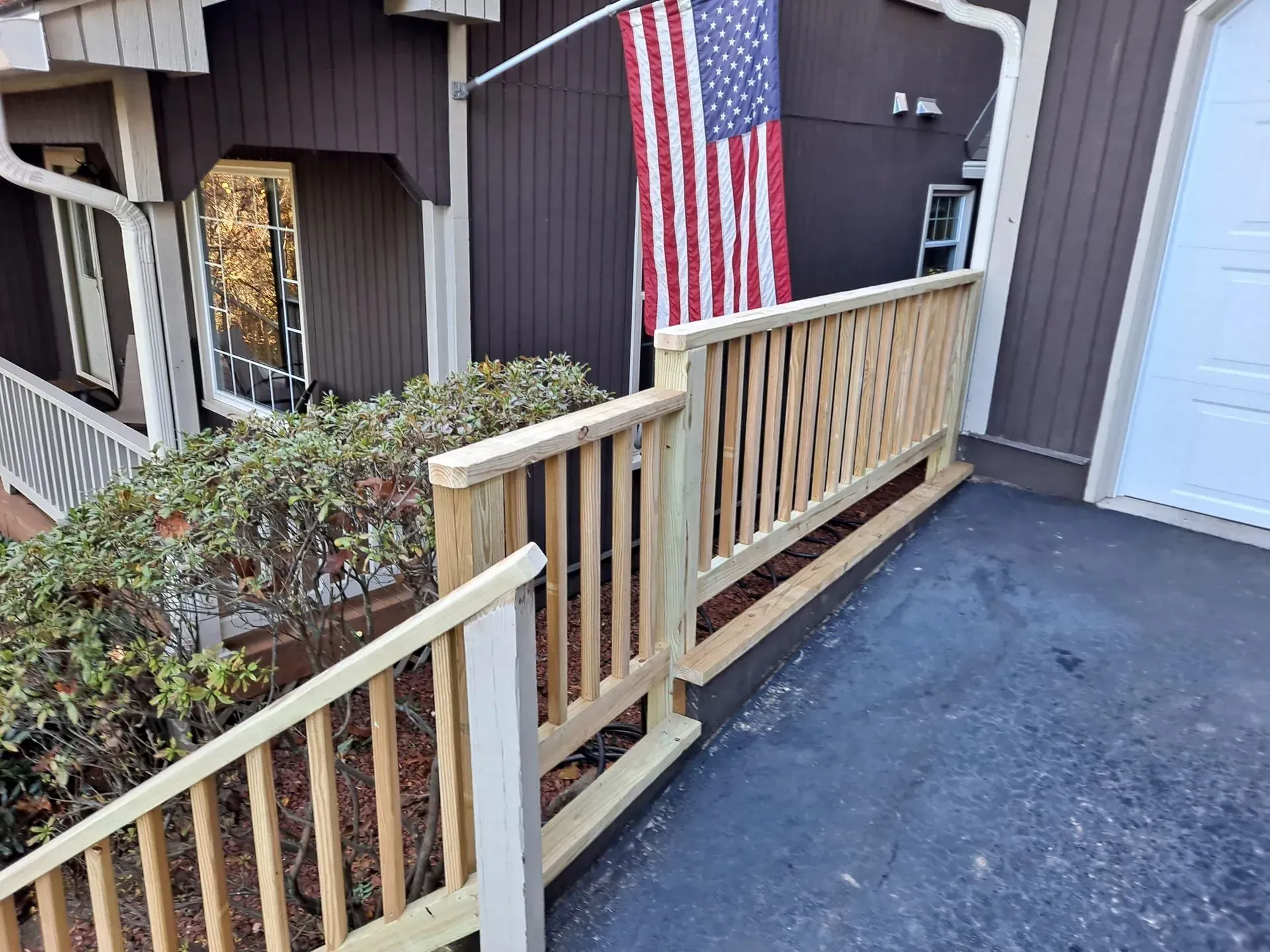 Wooden ramp and railing, painted brown house with American flag.