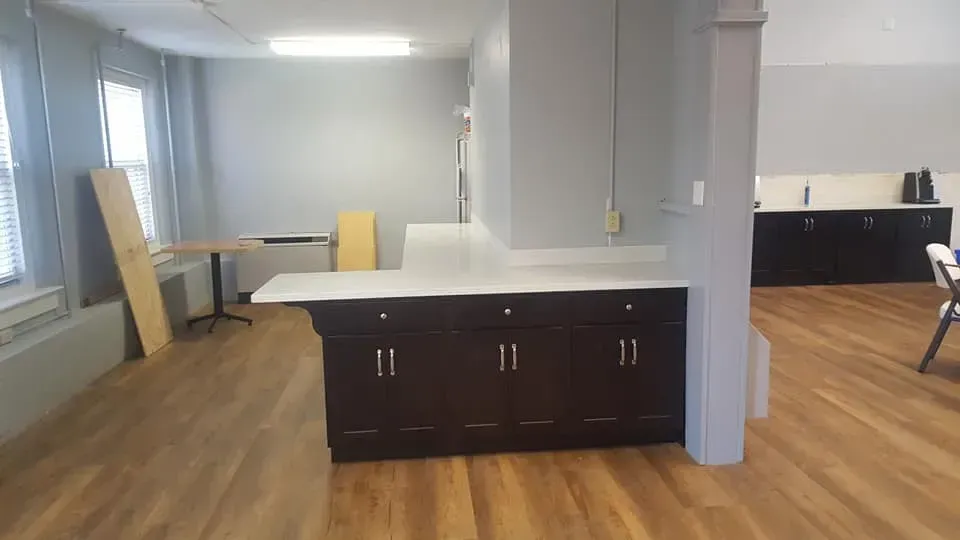 Kitchen area with dark brown cabinets, white countertop, and light brown wood flooring.