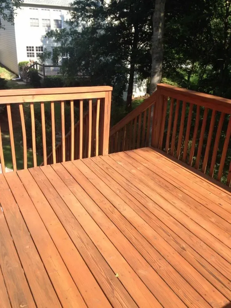 Wooden deck with railings stained a reddish-brown color, leading to a slightly lower level.