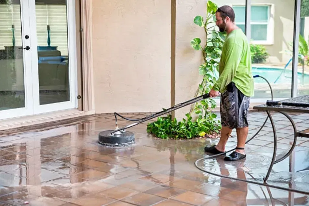 Man power washing a patio with a circular cleaner.