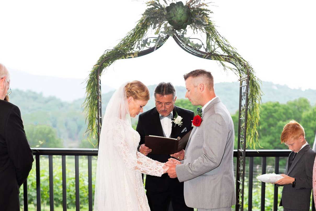 A bride and groom are holding hands during their wedding ceremony.