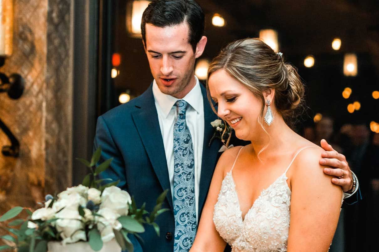 A bride and groom are cutting their wedding cake together.