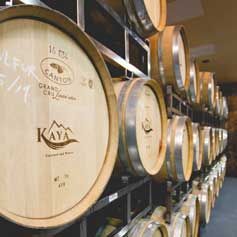 A row of wooden wine barrels stacked on top of each other in a wine cellar.