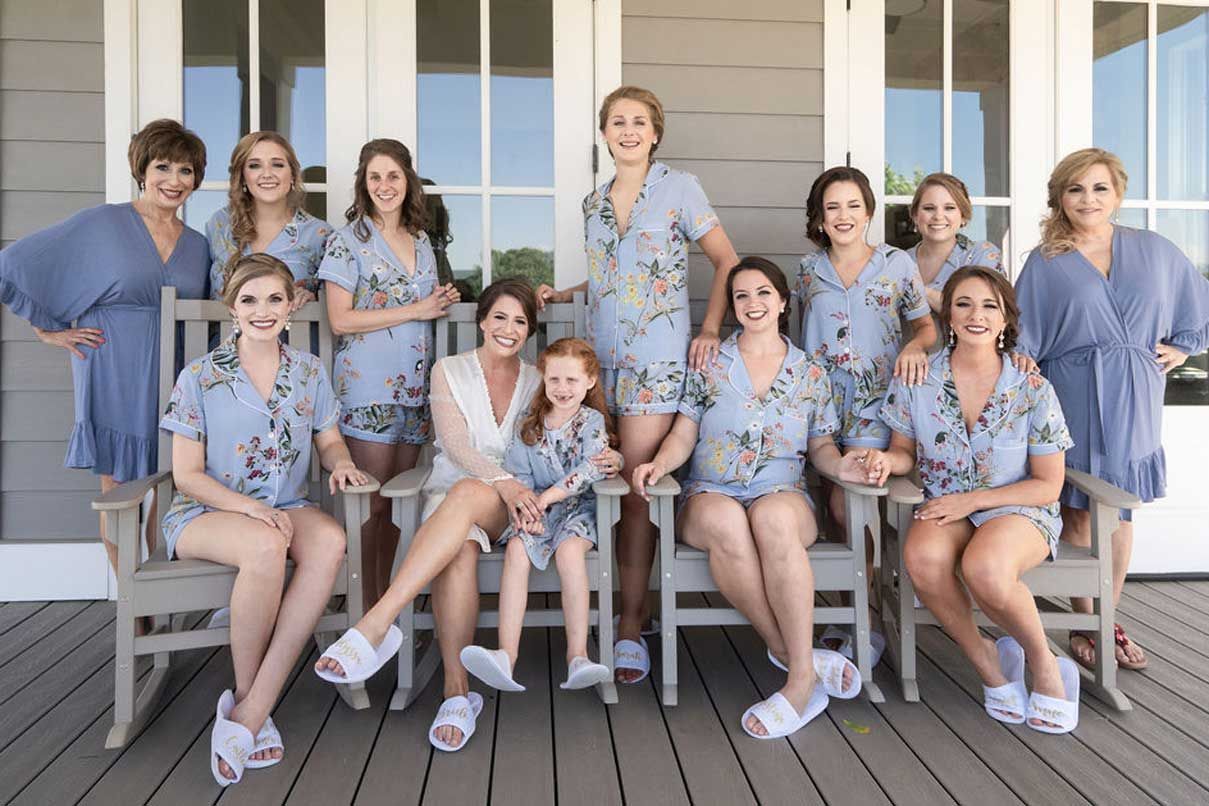 A group of women are sitting on rocking chairs on a porch.