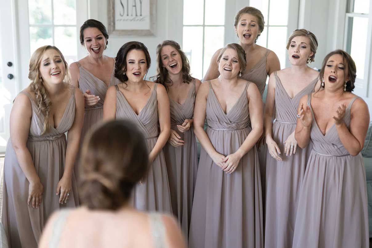 A bride and her bridesmaids are standing in front of a mirror.