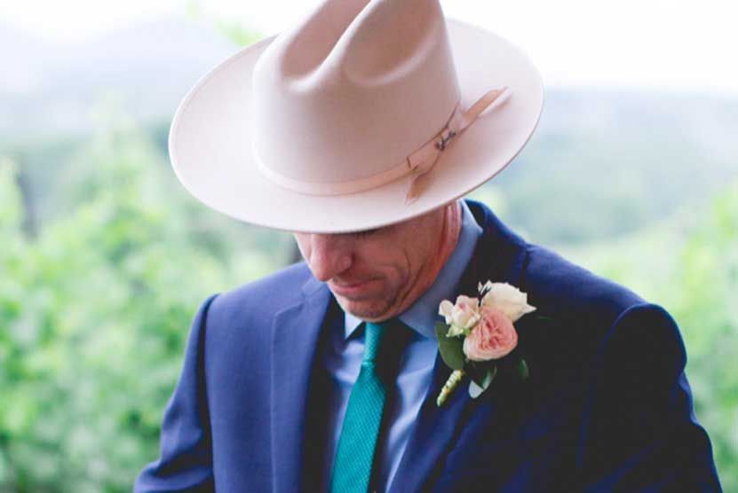 A man in a suit and hat is looking down.