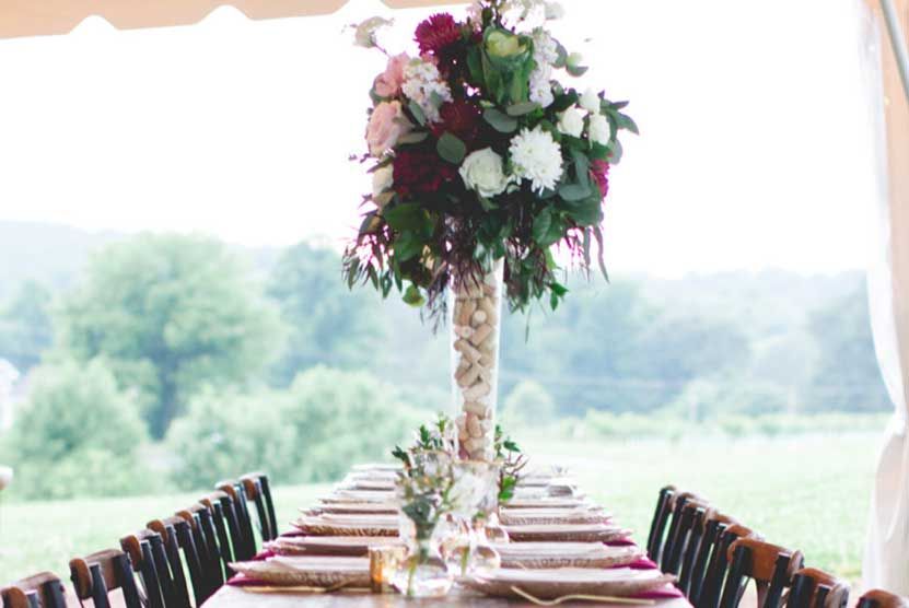 A long table with a vase of flowers on it under a tent.