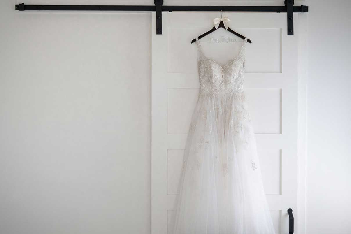 A wedding dress is hanging on a sliding barn door.