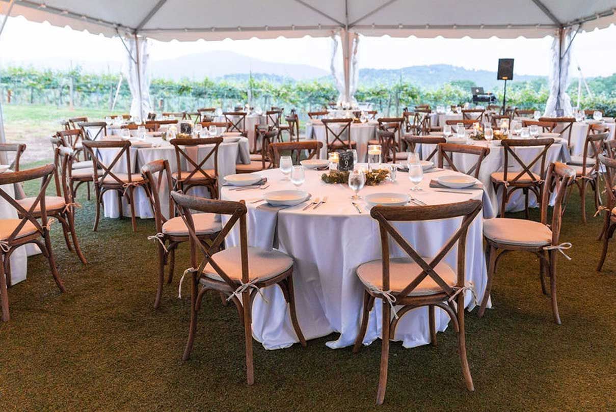 A tent with tables and chairs set up for a wedding reception.