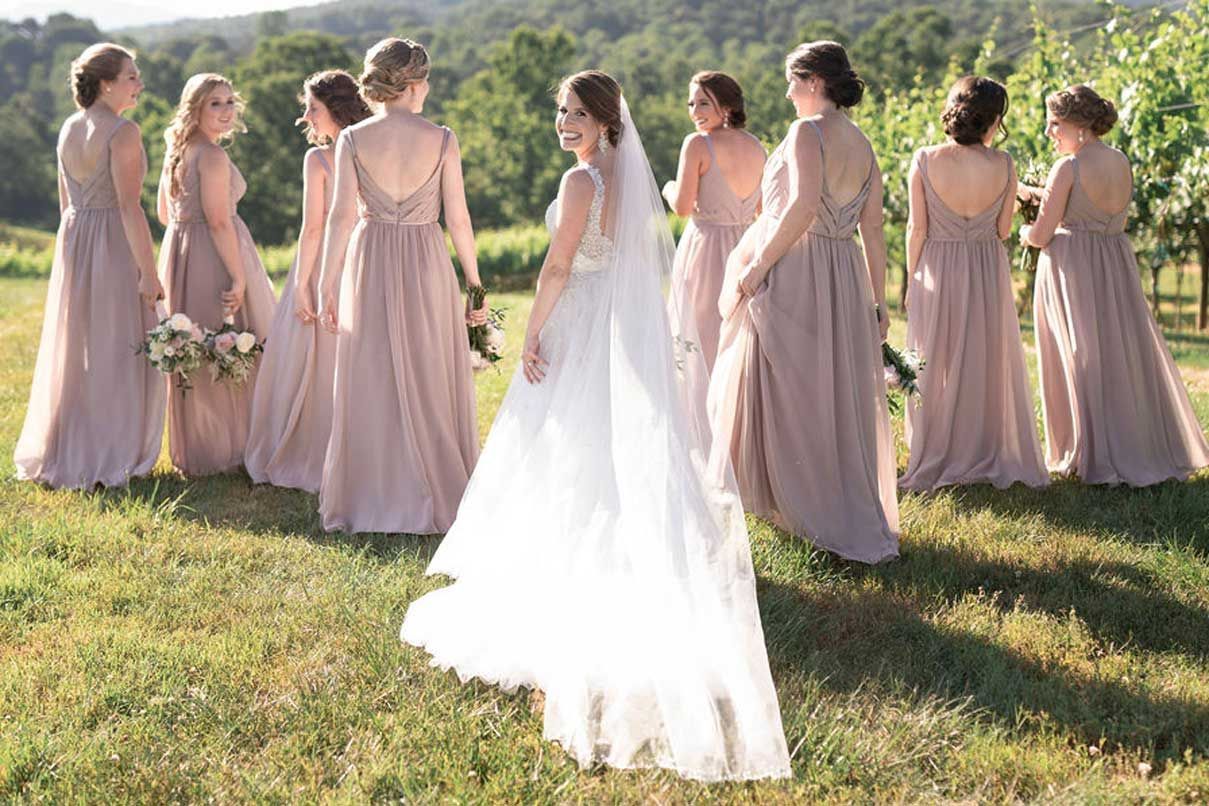 A bride and her bridesmaids are posing for a picture in a field.