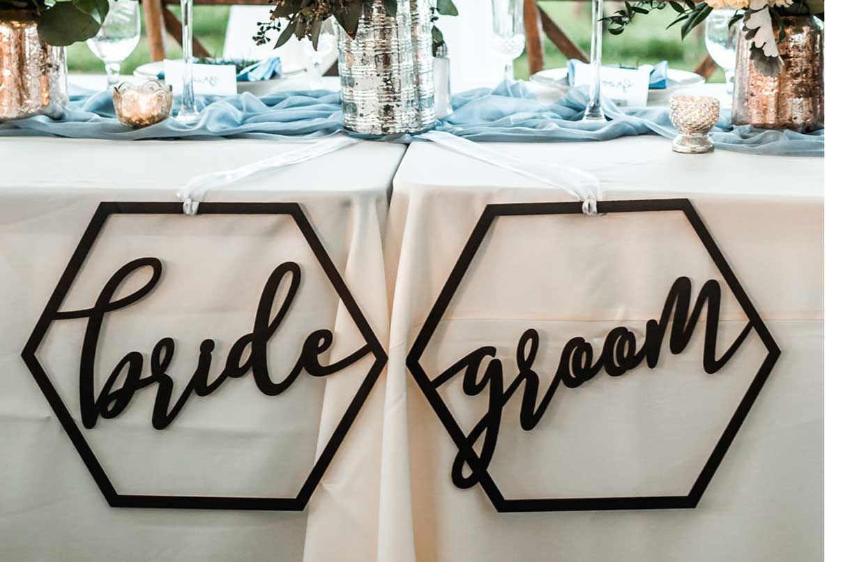A bride and groom sign is hanging on a table.