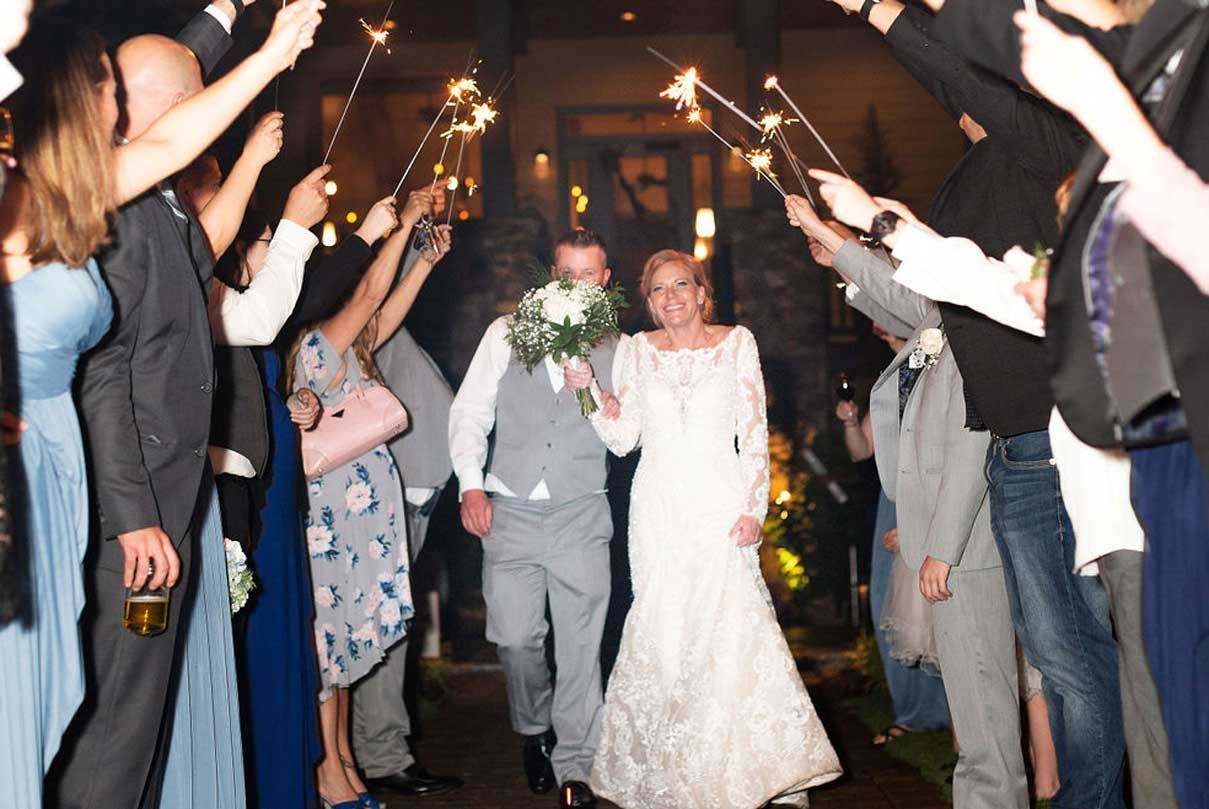 A bride and groom are walking through a tunnel of sparklers.