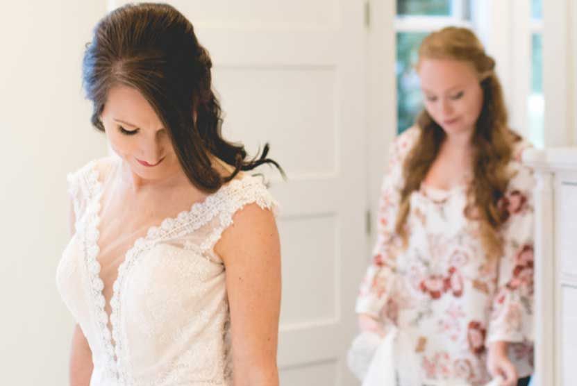 A woman in a wedding dress is standing next to a woman in a floral dress.
