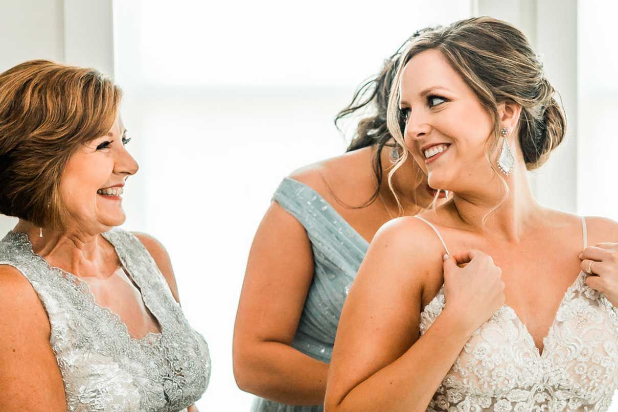 A bride is getting ready for her wedding with her mother and bridesmaid.