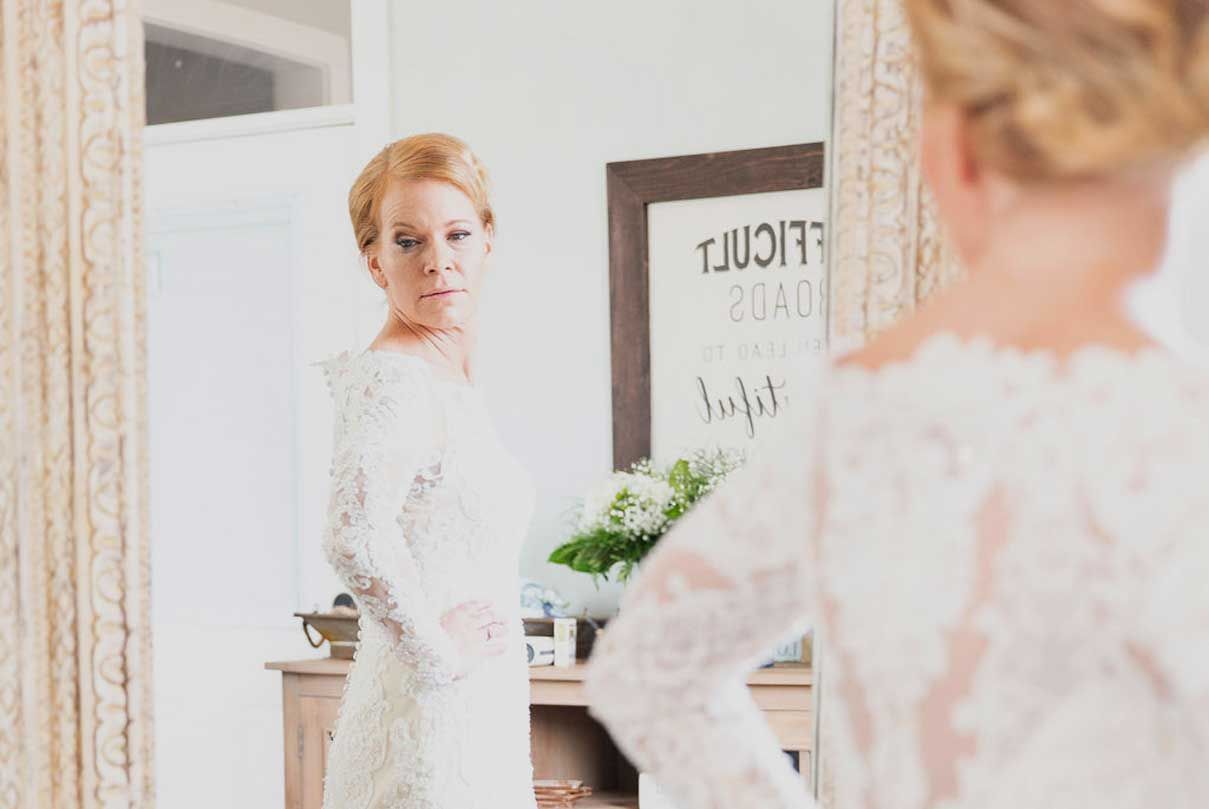 A woman in a wedding dress is looking at herself in a mirror.
