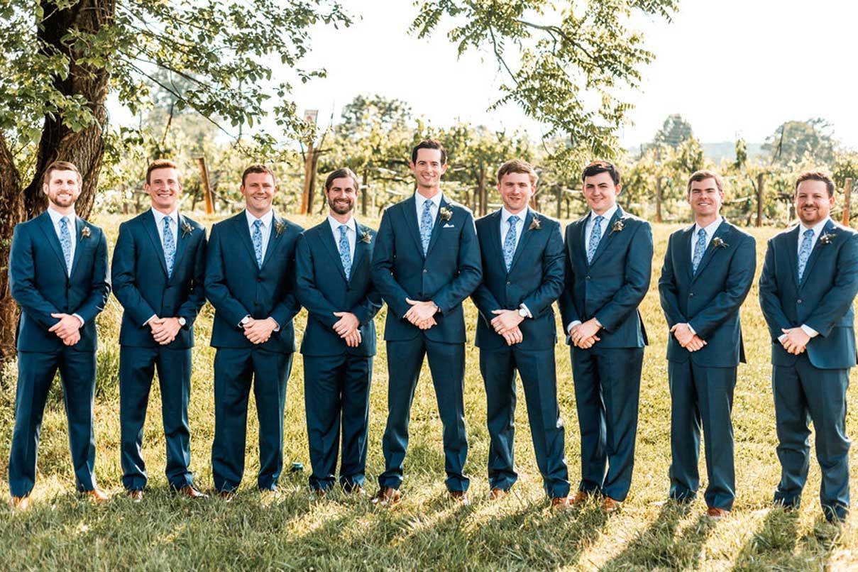 A group of men in suits and ties are standing in a field.
