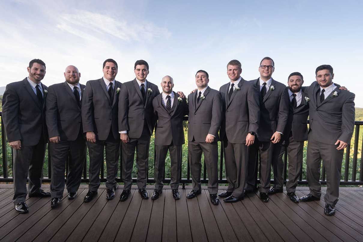 A group of men in suits and ties are posing for a picture on a deck.