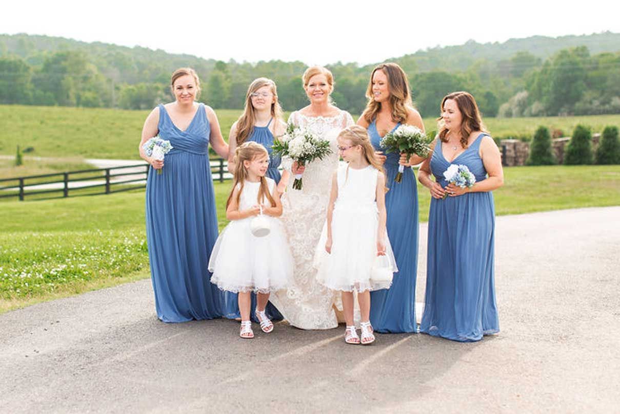 A bride and her bridesmaids are standing next to each other on a road.