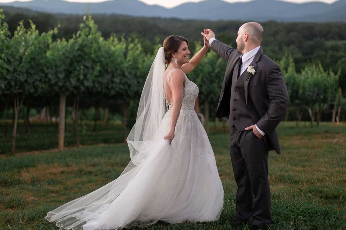 A bride and groom are dancing in a vineyard.