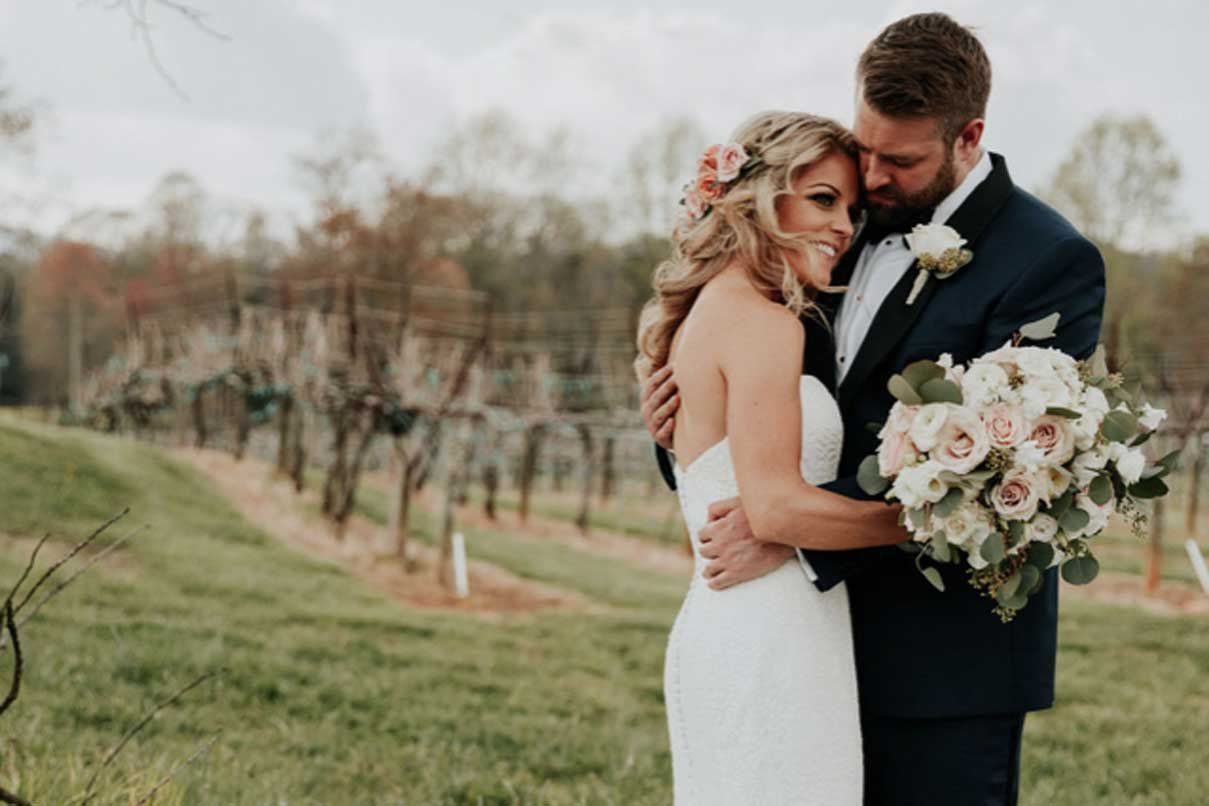 A bride and groom are posing for a picture in a field.