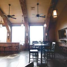 A restaurant with tables and chairs and ceiling fans.