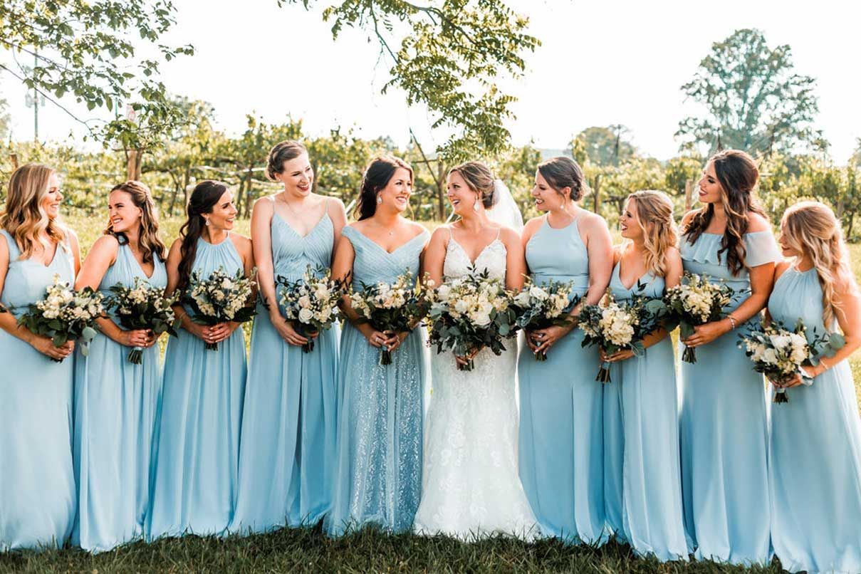 A bride and her bridesmaids are posing for a picture in a field.
