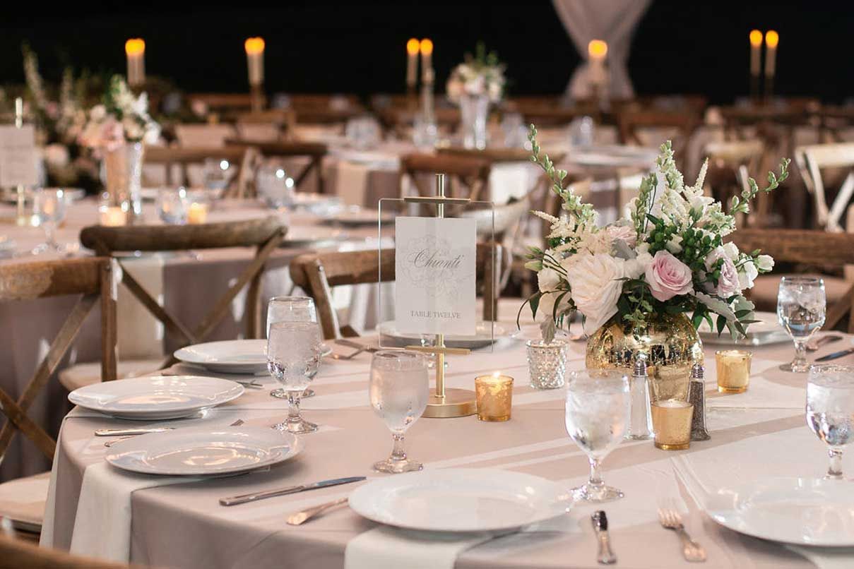 A table set for a wedding reception with plates , glasses , candles and flowers.