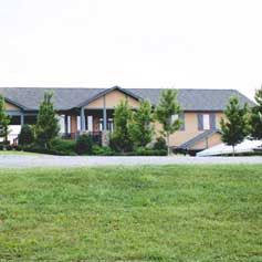 A large house is sitting on top of a lush green field.