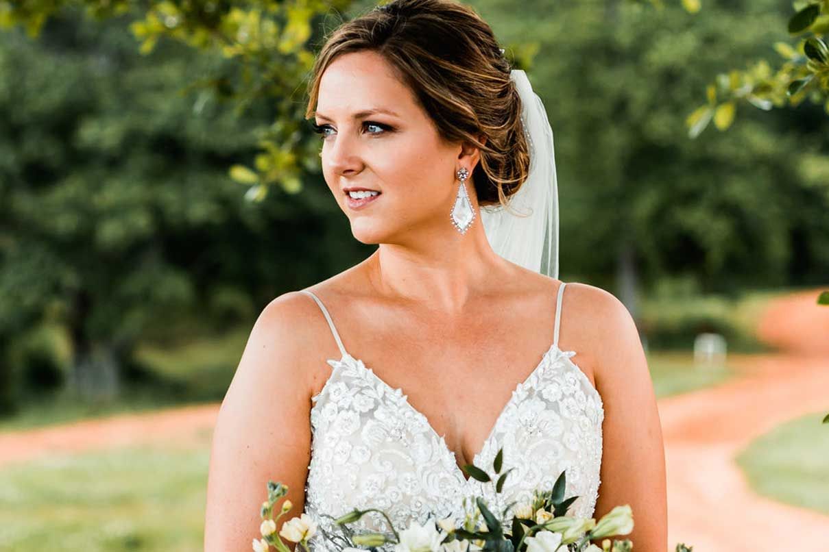 A bride in a white dress and veil is holding a bouquet of flowers.
