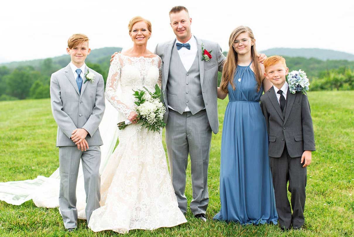A bride and groom are posing for a picture with their children.