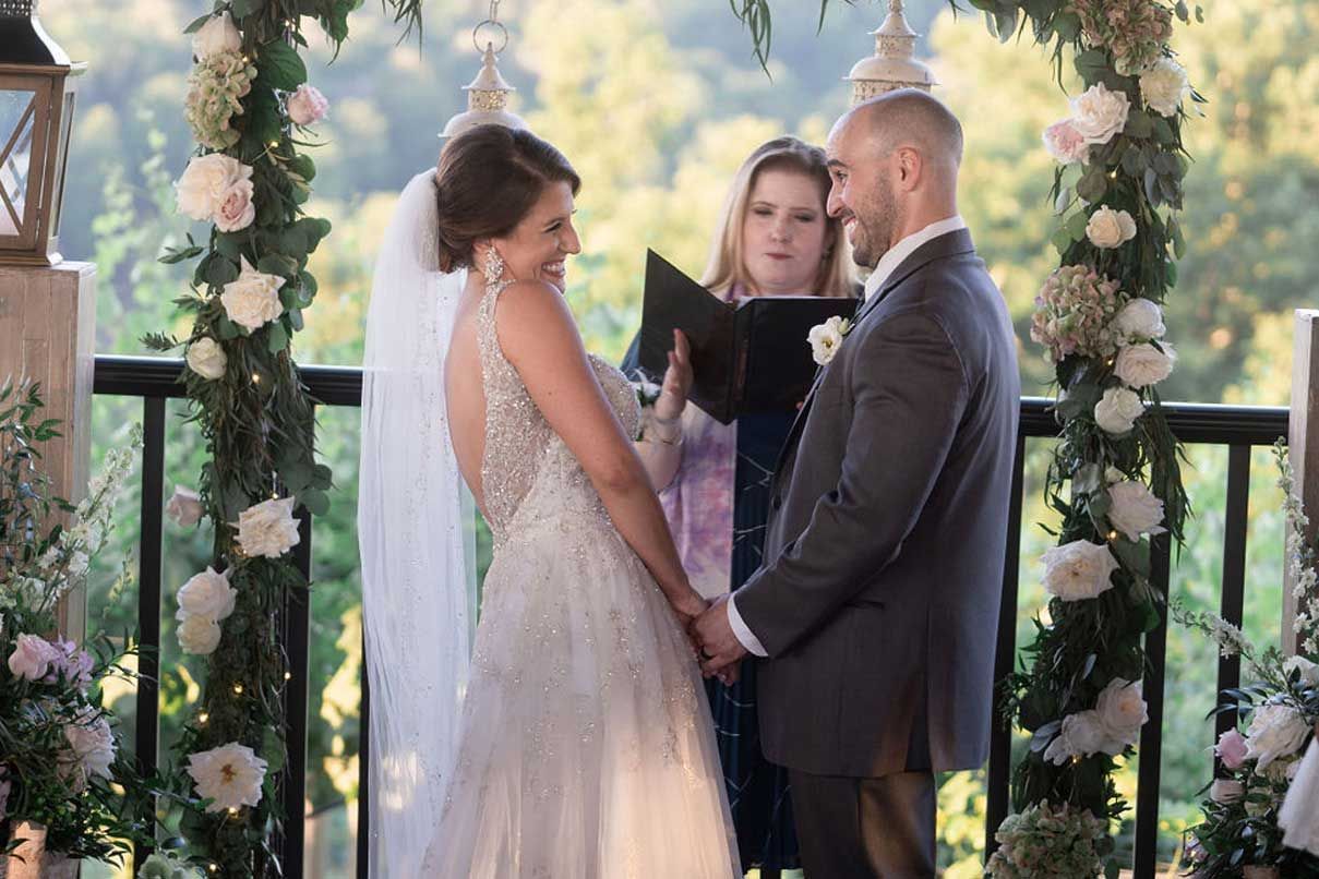 A bride and groom are holding hands during their wedding ceremony.