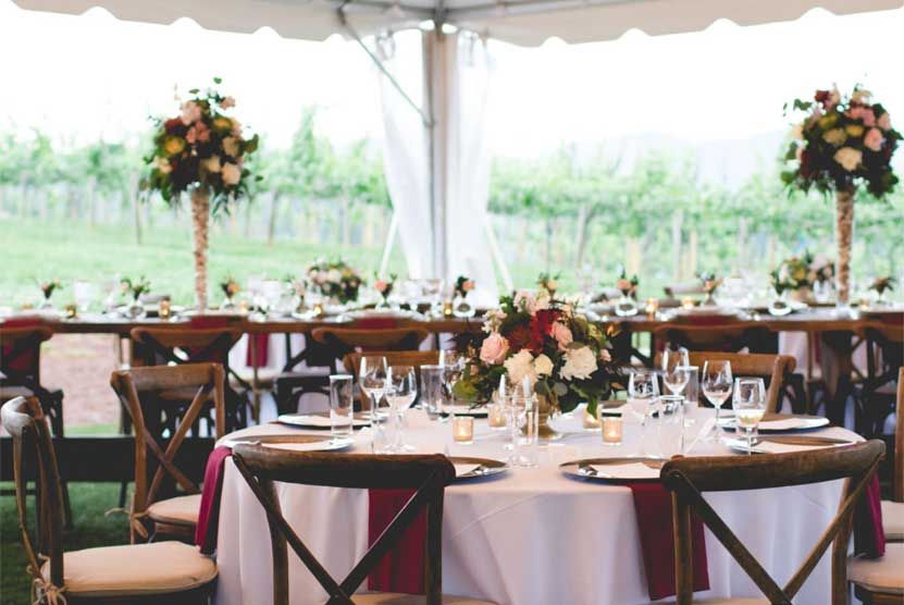 A table and chairs are set for a wedding reception under a tent.