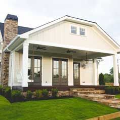 A white house with a porch and stairs in front of it.