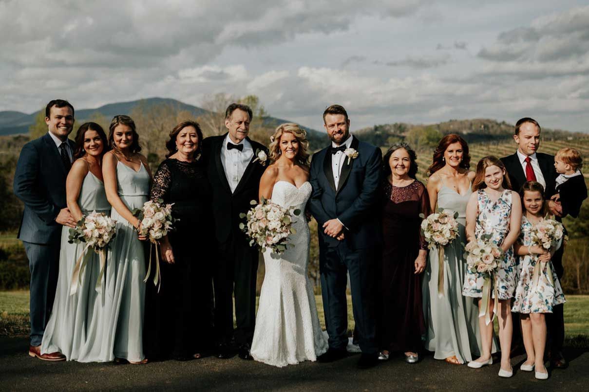 A bride and groom are posing for a picture with their wedding party.