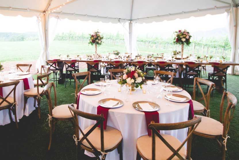 A tent with tables and chairs set up for a wedding reception.