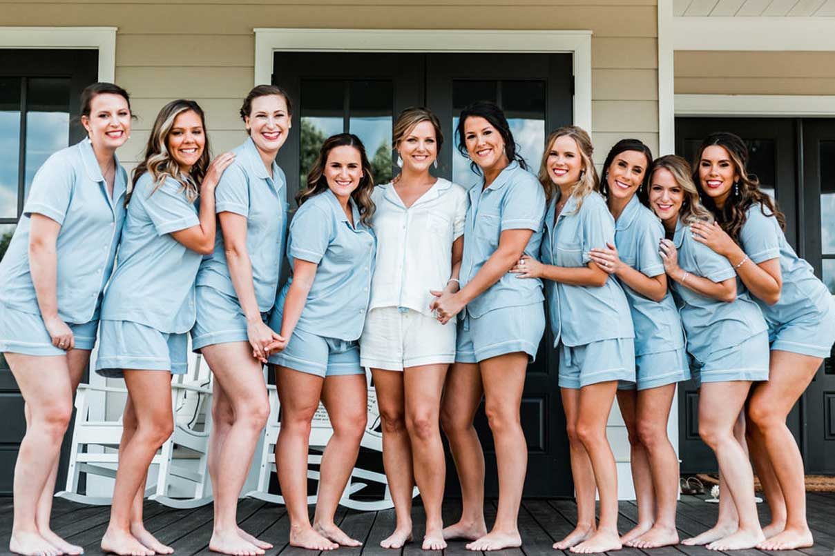 A bride and her bridesmaids are posing for a picture in front of a house.