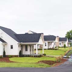 A row of white houses with black roofs in a residential area.