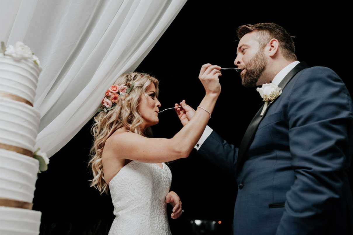 A bride and groom are feeding each other cake at their wedding reception.