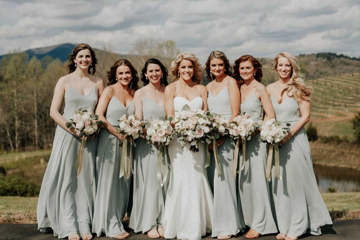 A bride and her bridesmaids are posing for a picture.