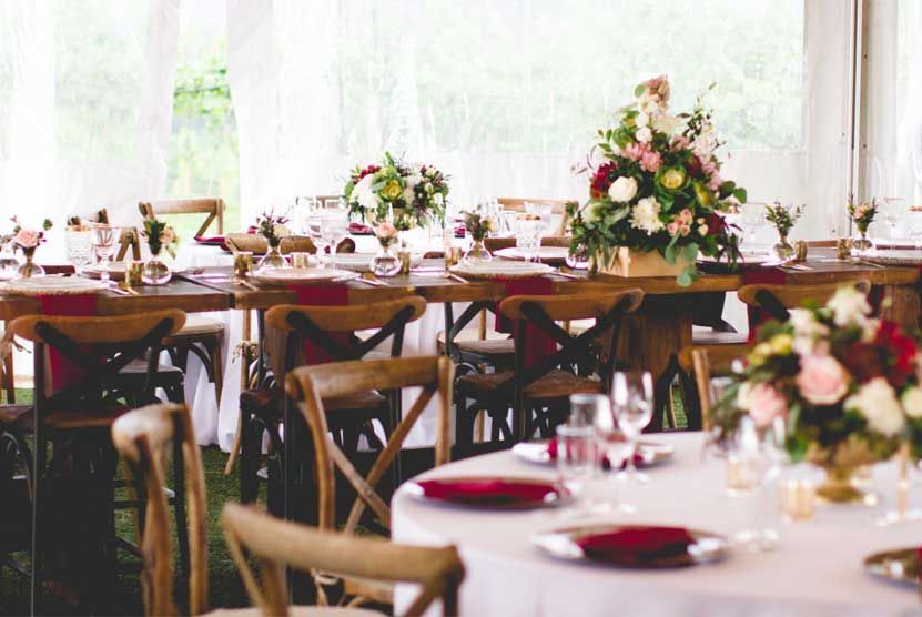 A dining room with tables and chairs set up for a wedding reception.