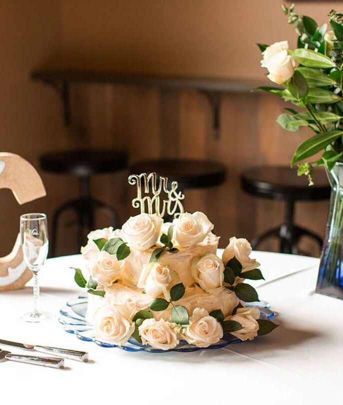 A wedding cake with roses and a cake topper that says mr. and mrs.