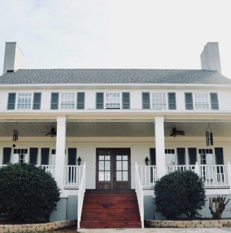 A large white house with a porch and stairs