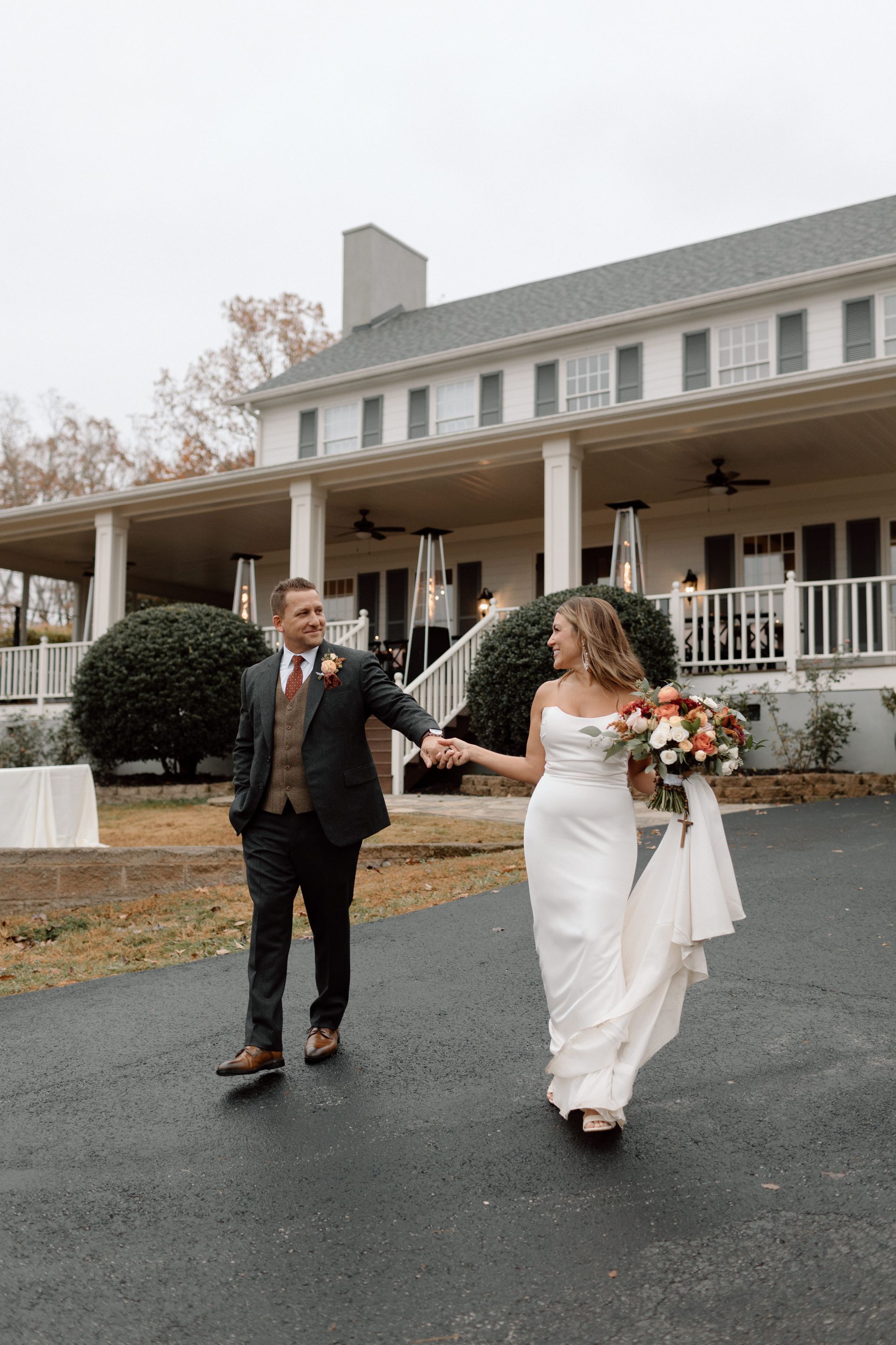 A bride and groom are standing in a grassy field looking at each other.