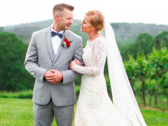 A bride and groom are standing next to each other in a field.