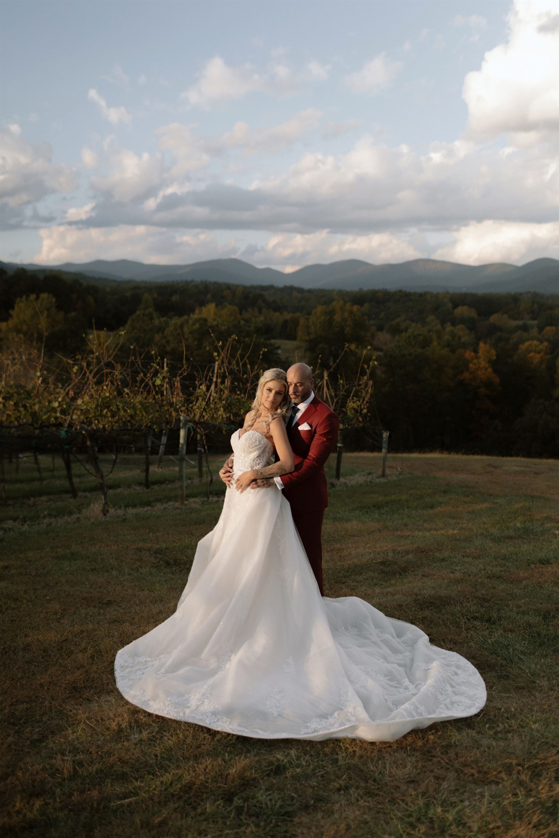 A bride and groom are kissing under an umbrella in a field.