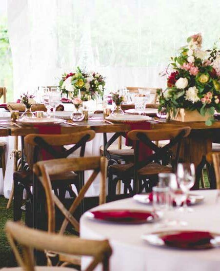 A dining room with tables and chairs set up for a wedding reception.