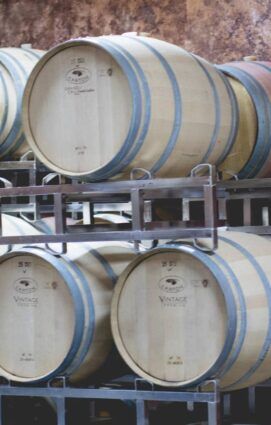 A bunch of wine barrels are stacked on top of each other.