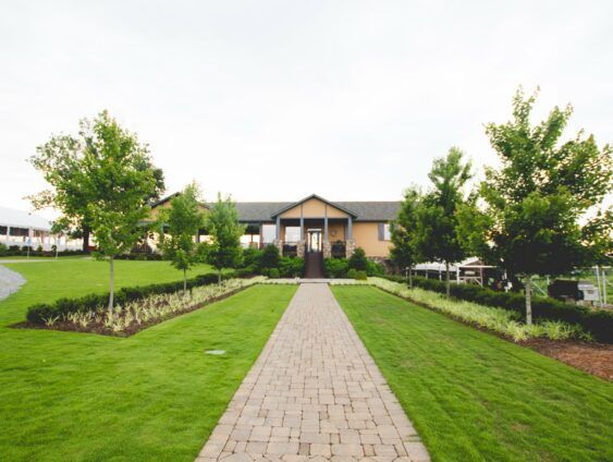 A brick walkway leading to a large house