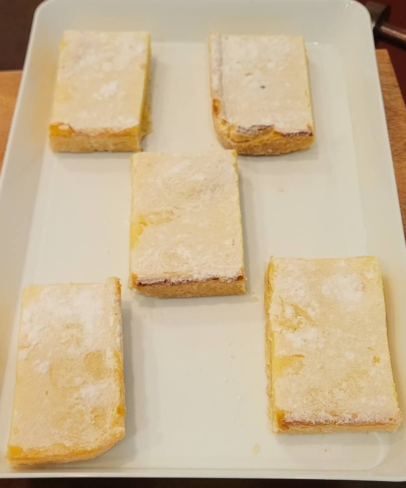 Three strawberry-topped donuts with pink frosting and powdered sugar.