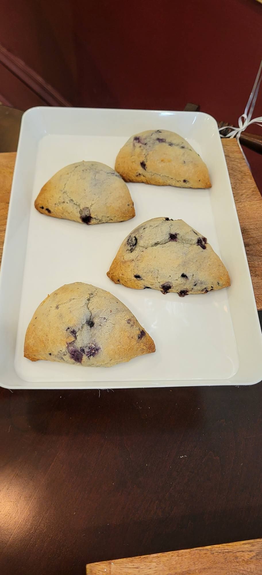 Three-tiered wedding cake with orange and white flowers, on a wooden base.